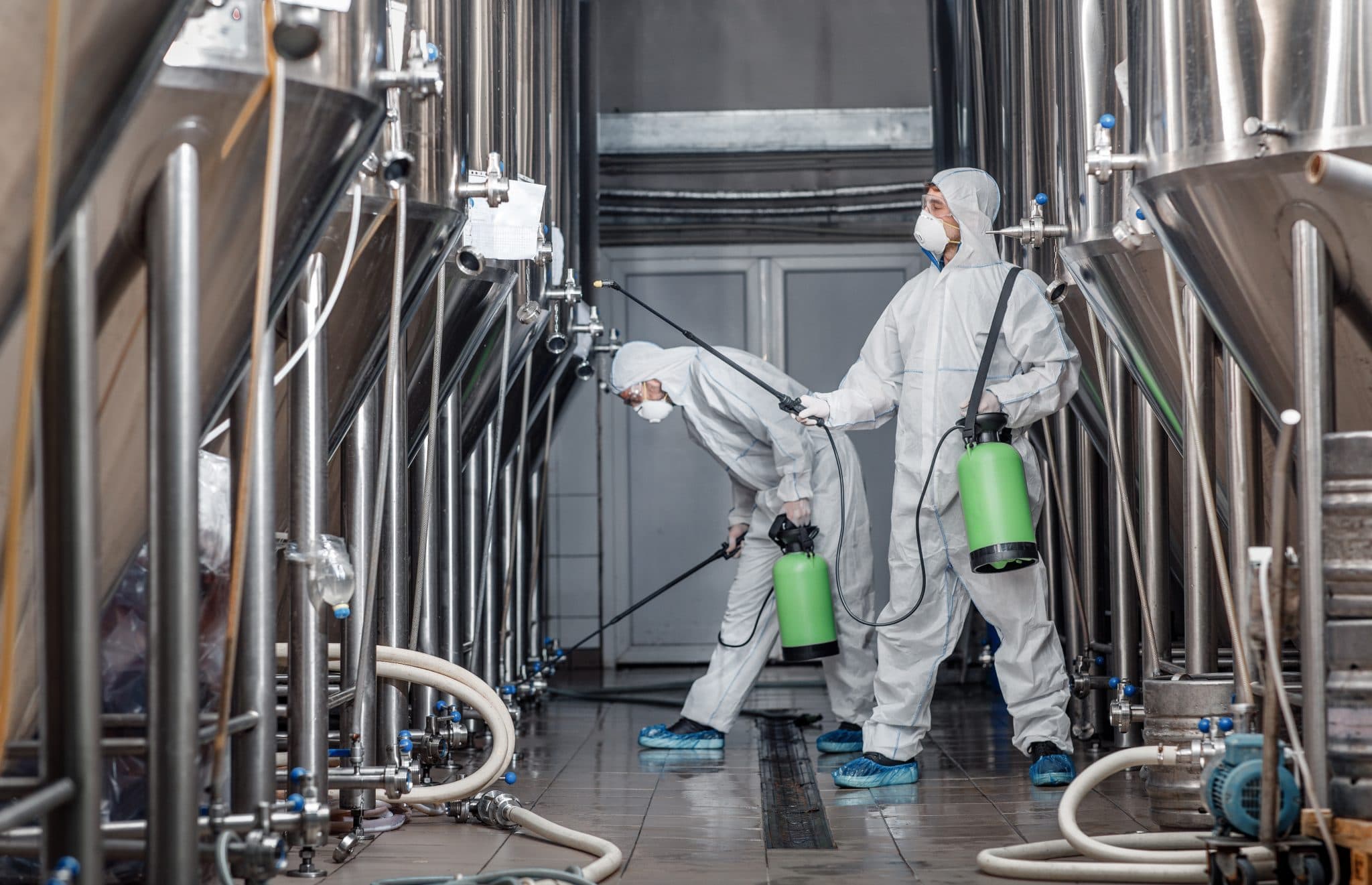 Kesselreinigung im Industriebetrieb – Fachkräfte in Schutzausrüstung reinigen Edelstahlbehälter
