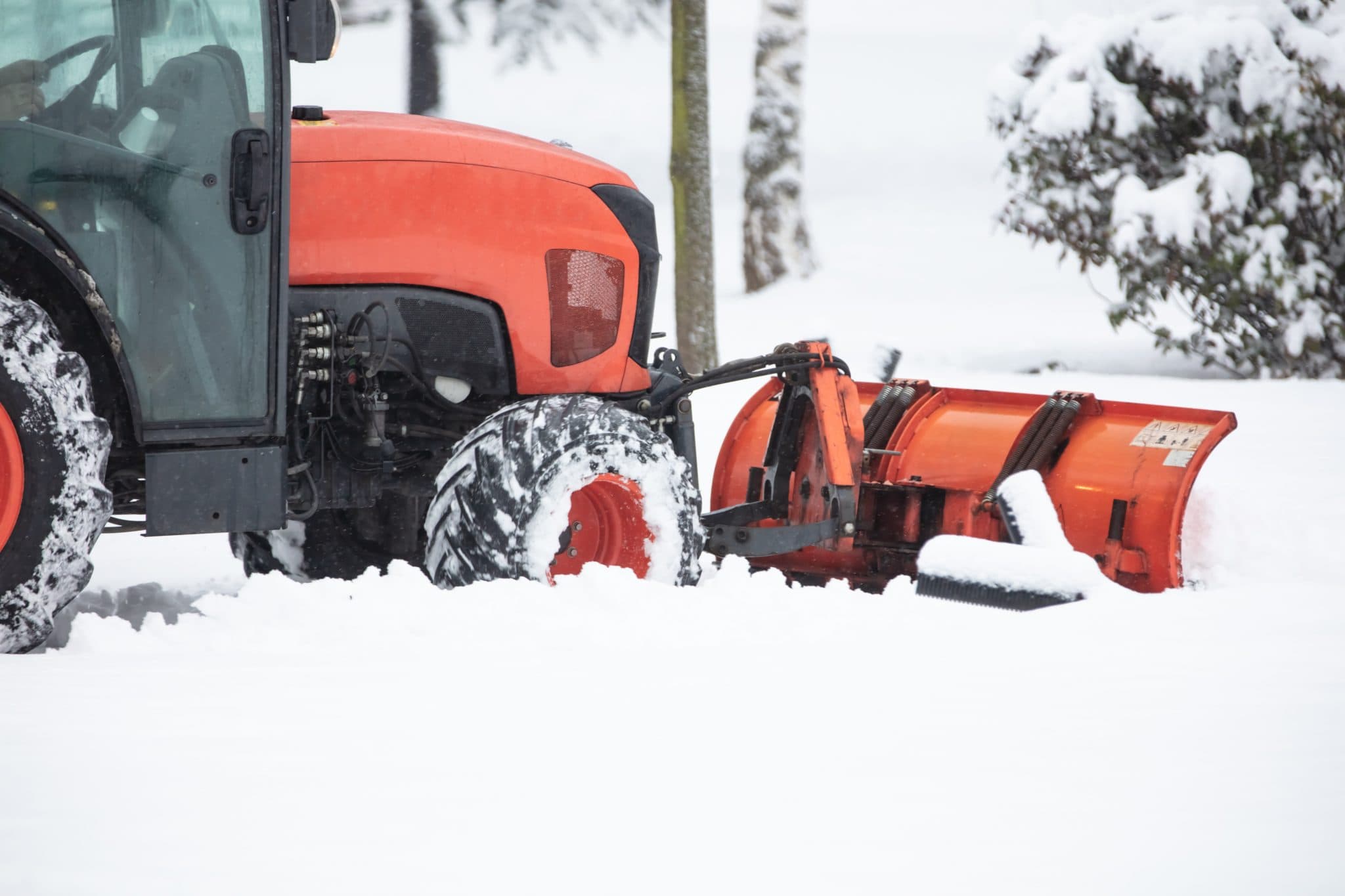 Traktor mit Räumschild beim Schneeräumen