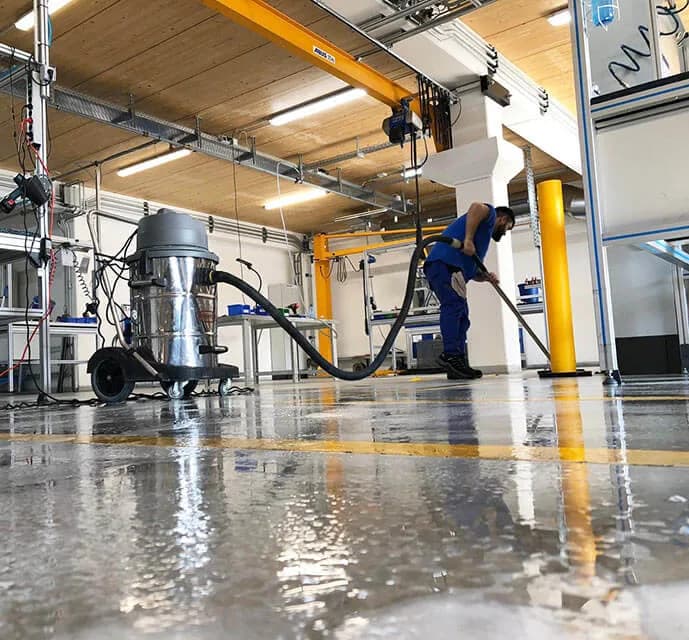 Nassreinigung eines Hallenbodens mit Industriesauger in einer Fertigungshalle
