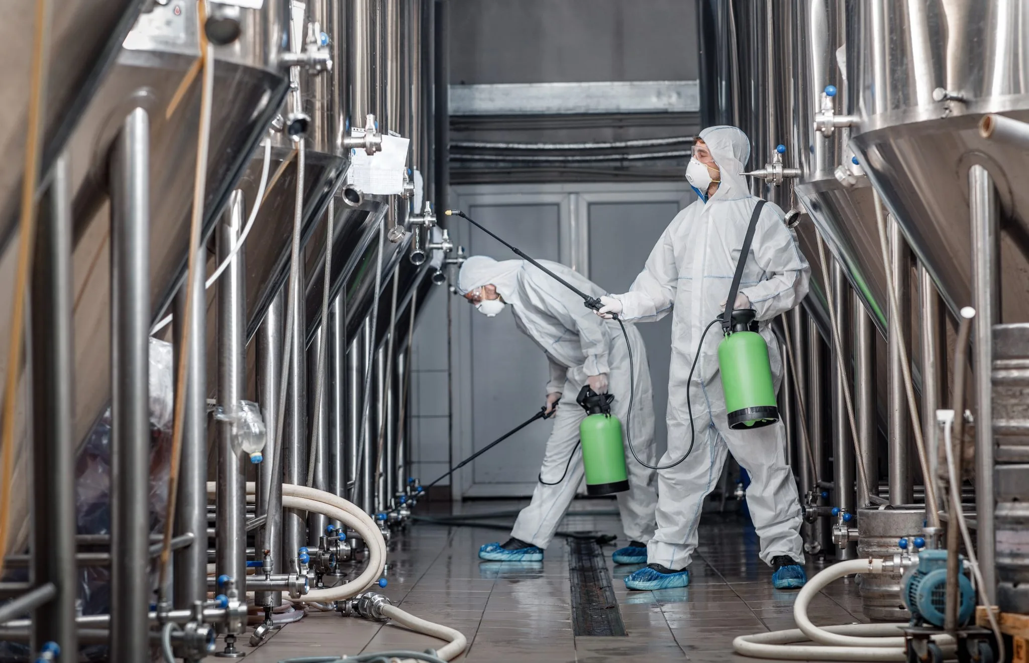 Kesselreinigung im Industriebetrieb – Fachkräfte in Schutzausrüstung reinigen Edelstahlbehälter